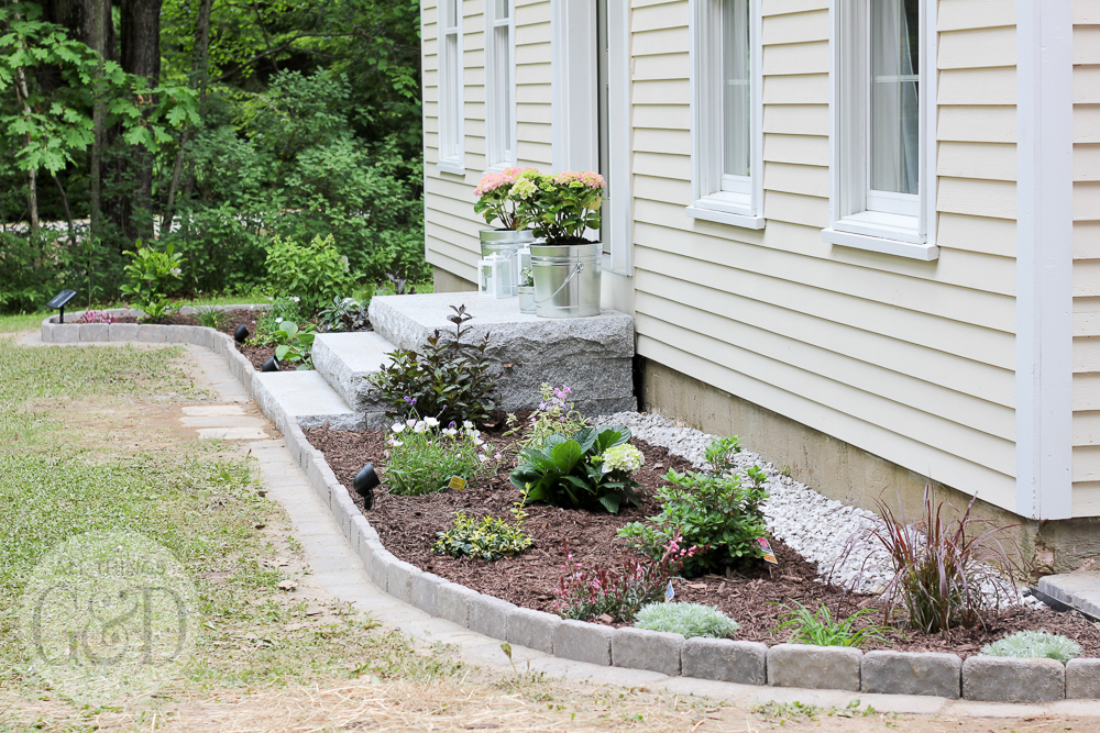 Lowe's Front Yard Makeover in Portland, Maine featuring a new paver patio, outdoor decorations, Pella carriage style garage door, and trim-free landscape edging.